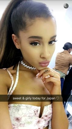 a woman with long hair wearing a white top and silver necklace, posing for the camera