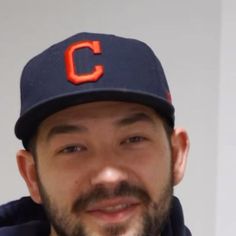 a close up of a baseball player wearing a hat and looking at the camera with a smile on his face