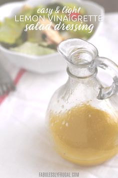 a glass pitcher filled with lemon vinaigrette salad dressing next to a bowl of salad