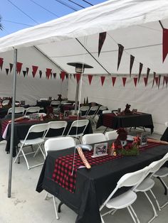 tables and chairs are set up under a tent with red and black tablecloths