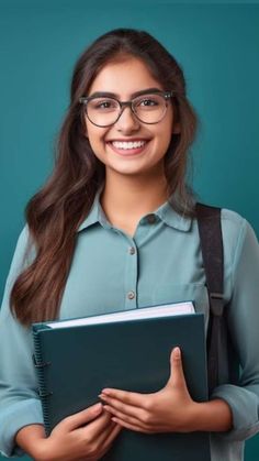 a woman with glasses holding a book and smiling