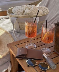 two glasses and a wallet are sitting on a wooden table with some drinks in it