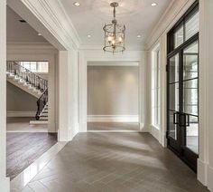 an empty hallway with stairs and chandelier