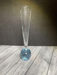 a tall glass vase sitting on top of a wooden table next to a light bulb