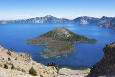 an island in the middle of water surrounded by mountains