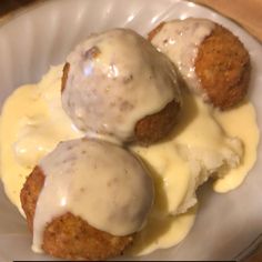 three meatballs covered in gravy on top of a white plate with sauce