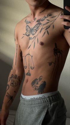 a man with many tattoos on his chest holding a cell phone in front of him