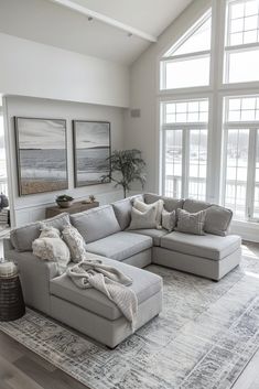 a living room with large windows and a sectional couch in front of the window on top of an area rug