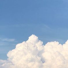 an airplane is flying high in the sky above some white fluffy clouds on a sunny day