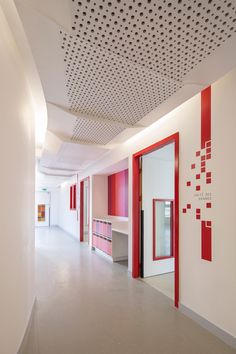 an empty room with red and white accents on the walls, along with large mirrors