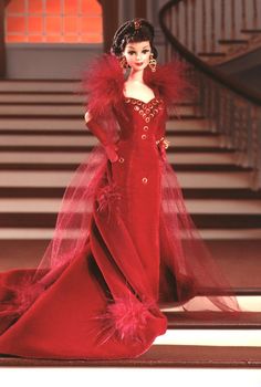 a barbie doll wearing a red gown with feathers on it's head and shoulders