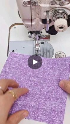 someone is using a sewing machine to sew fabric on a piece of purple material