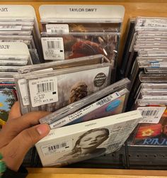 a person is holding some cds in their hand and they are on the shelf with other cd's