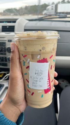 a person holding up a cup of coffee with sprinkles on it