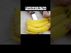 a bunch of bananas sitting on top of a counter next to a person cutting them