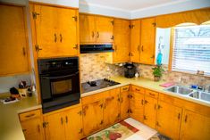 a kitchen with wooden cabinets and an oven in the corner, next to a sink