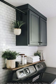 a washer and dryer in a room with white tiles on the wall, black cabinets