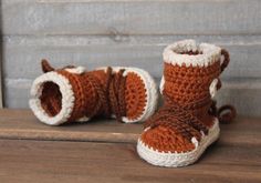 a pair of crocheted baby boots sitting on top of a wooden table