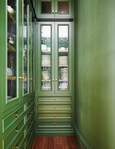 an empty room with green cabinets and wood floors