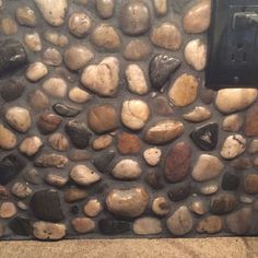 a wall made out of rocks with a light switch in the middle and an electrical outlet on one side