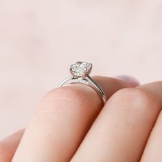 a close up of a person's hand holding a ring with a diamond on it