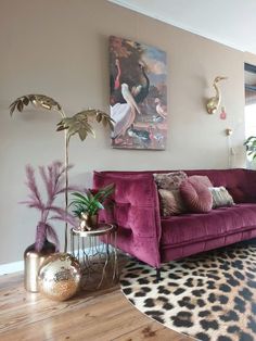 a living room with a purple couch and some potted plants on the table in front of it