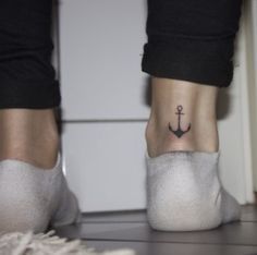 an anchor tattoo on the ankle of a woman's foot, while she is wearing white socks