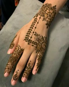 a henna tattoo on the palm of someone's hand with flowers and vines