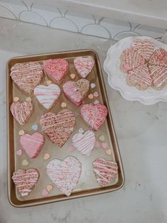 some heart shaped cookies are on a baking sheet next to a plate with one cut in half