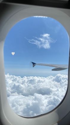 the view out an airplane window shows clouds and a heart shaped object in the sky