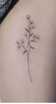 a small flower tattoo on the back of a woman's shoulder