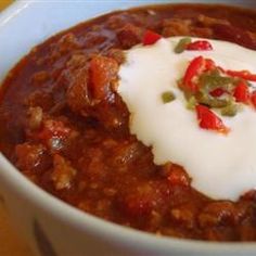 a white bowl filled with chili and sour cream