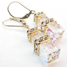 Modern style bride earrings are a luminescent sparkly Swarovski crystal dream. Gorgeous clear Swarovski crystal cubes are accented with Swarovski rhinestone crowns to make a modern take on traditional bridal earrings. Set on 14k gold filled leverback earring closures for a secure fit while the bride dances the night away. A great gift for the bride for hew wedding day or a bridal related event. Earring Details: - Earring length is 1.50 inches (3.81 cm) including the leverback earring closures* * Bling Crystal Earrings For Anniversary, Dangle Crystal Earrings With Bling For Anniversary, White Sparkling Crystal Earrings, White Bling Crystal Earrings For Wedding, Sparkling White Crystal Earrings, Dazzling White Dangle Crystal Earrings, Dazzling White Crystal Dangle Earrings, Sparkling Crystal Earrings For Celebration, Anniversary Bridal Bling Crystal Earrings