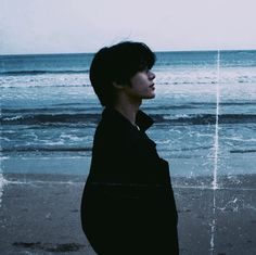 a man standing on top of a beach next to the ocean