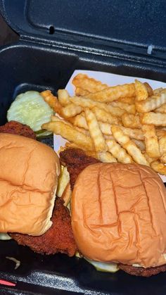 two hamburgers and fries in a black container