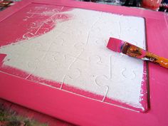 a pink board with white paint on it and a red brush resting on the top