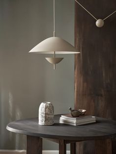 a table that has some books on it and a lamp hanging from the ceiling over it