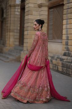 a woman in a pink lehenga walking down the street