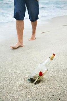 a man standing on the beach next to an empty bottle