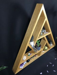 a wooden shelf with various items in it on a black surface next to a potted plant