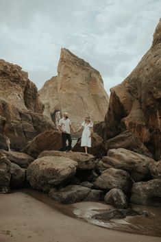 two people standing on rocks holding hands