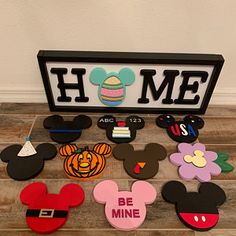 mickey mouse magnets are on the floor next to a sign that says, home