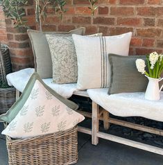 a bunch of pillows sitting on top of a wooden bench next to a brick wall