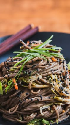 a black plate topped with noodles and vegetables