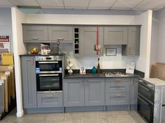 a kitchen with gray cabinets and stainless steel appliances in the middle of it's counter tops