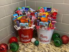 two buckets filled with candy sitting on top of a counter next to christmas decorations