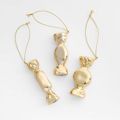 three pieces of gold jewelry sitting on top of a white surface, one is shaped like a cat and the other is shaped like a dog