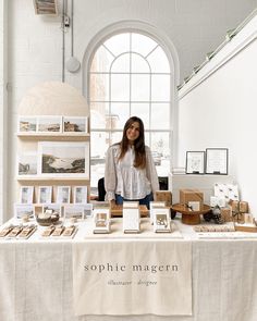 a woman standing in front of a table filled with books and other items on display