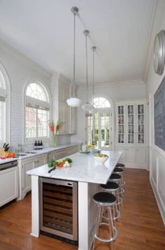 a kitchen with white cabinets and an island in the center, surrounded by bar stools