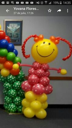 the balloon lady is standing next to her child's balloon bouquet in an office cubicle